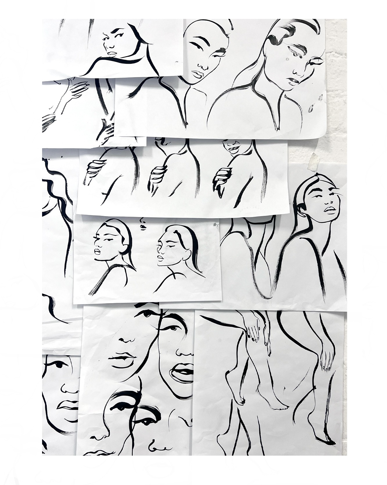 Beauty illustration work in progress on the studio wall. Sketches and papers on the studio wall  - black brush strokes for Olay brand. Body and  face and inky brush strokes style. Iconography illustrations, graphics minimal brushstrokes.