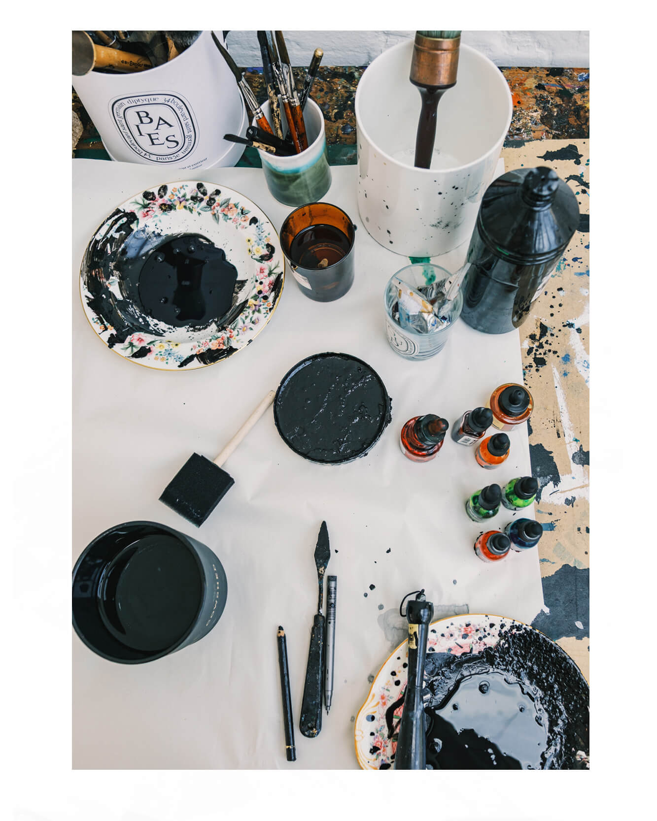 “Artist Caroline Tomlinson’s studio table with ink bottles, brushes, palettes and paint tools used for her expressive illustration process.