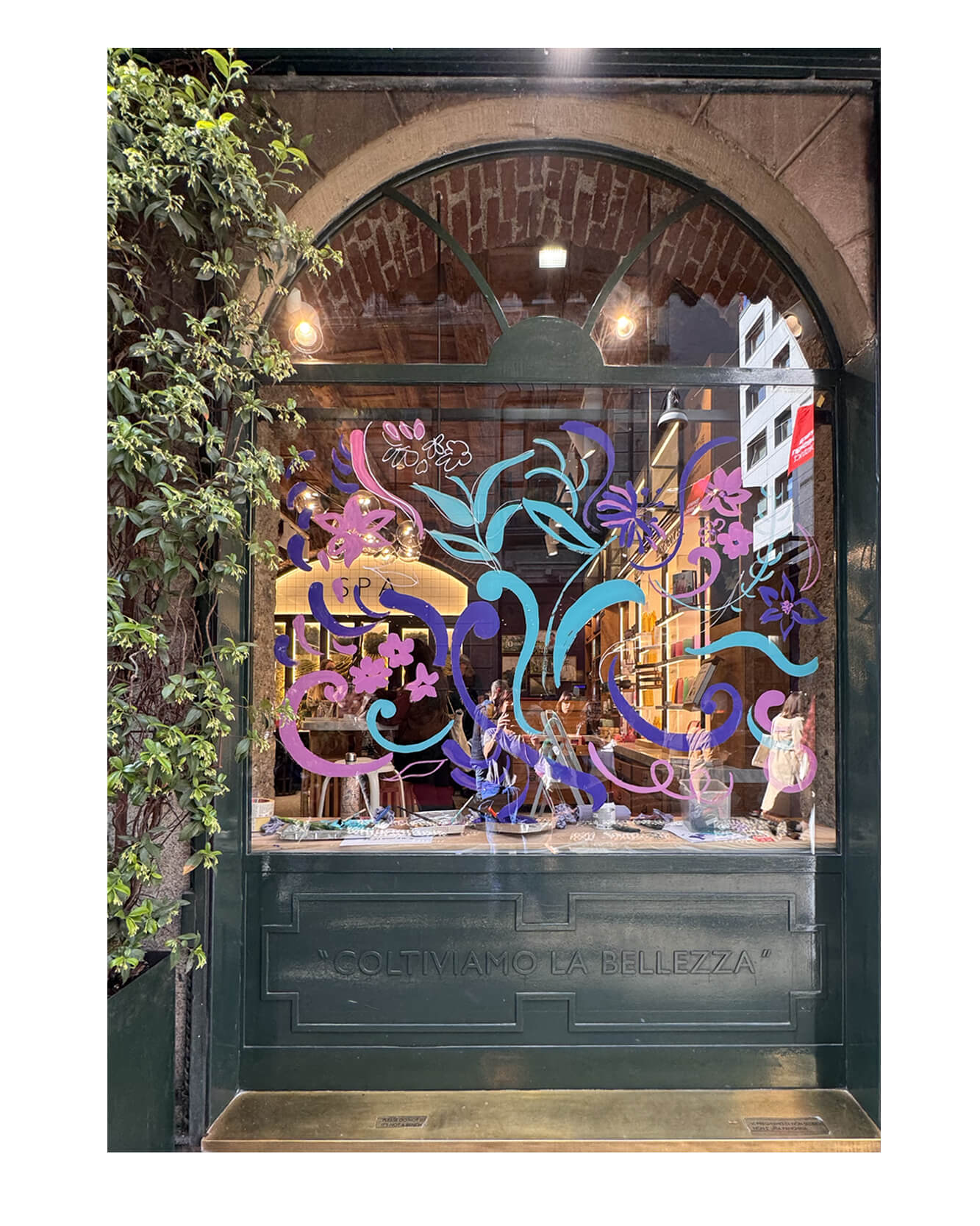 Artist live painting gestural botanical illustrations on large storefront windows during Milan Design Week for a luxury beauty brand, featuring fluid ink lines inspired by nature and fragrance.